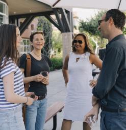 A student, parent, staff member, and instructor speaking at a program welcome dinner